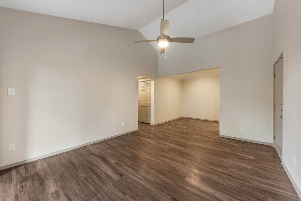 a living room with white walls and wood flooring and a ceiling fan